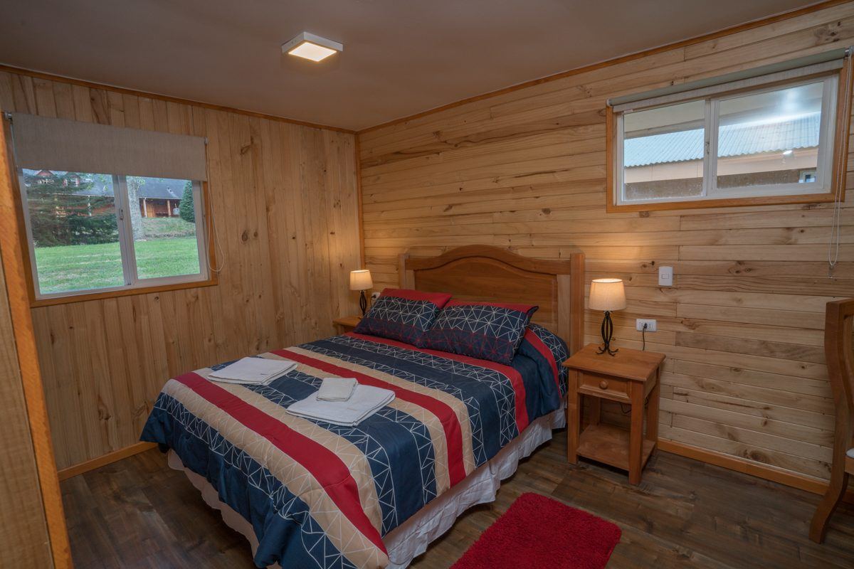 Quarto principal com cama de casal, criados-mudos e janela para o jardim