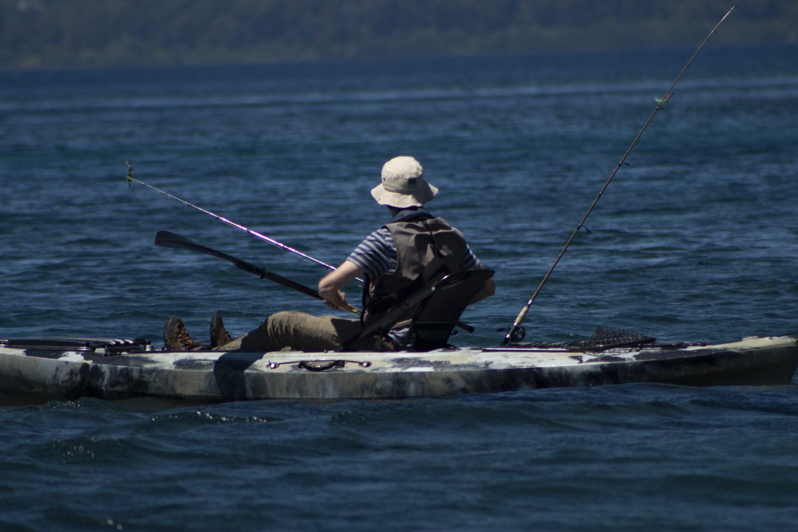 Pescador remando um caiaque no Lago Llanquihue, com varas de pesca a bordo