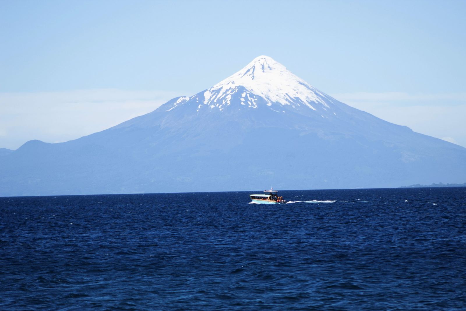 A lancha Lago Llanquihue navegando no lago em frente ao vulcão Osorno nevado