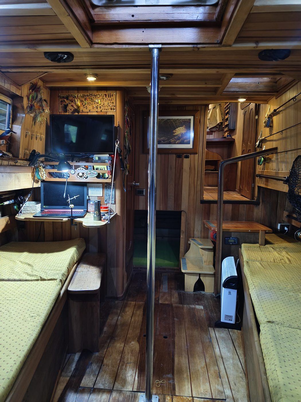 Interior do Lithium: cabine de madeira com assentos, varas de pesca e equipamento para montar moscas