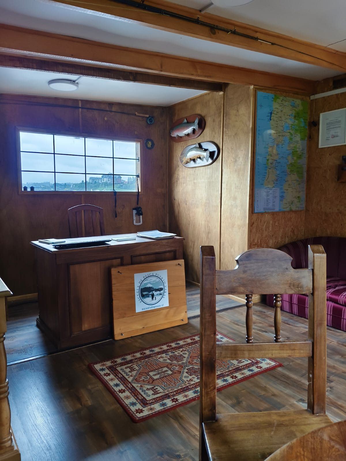 Balcão de atendimento com o logo da Escola de Pesca Puerto Varas e vista para o lago