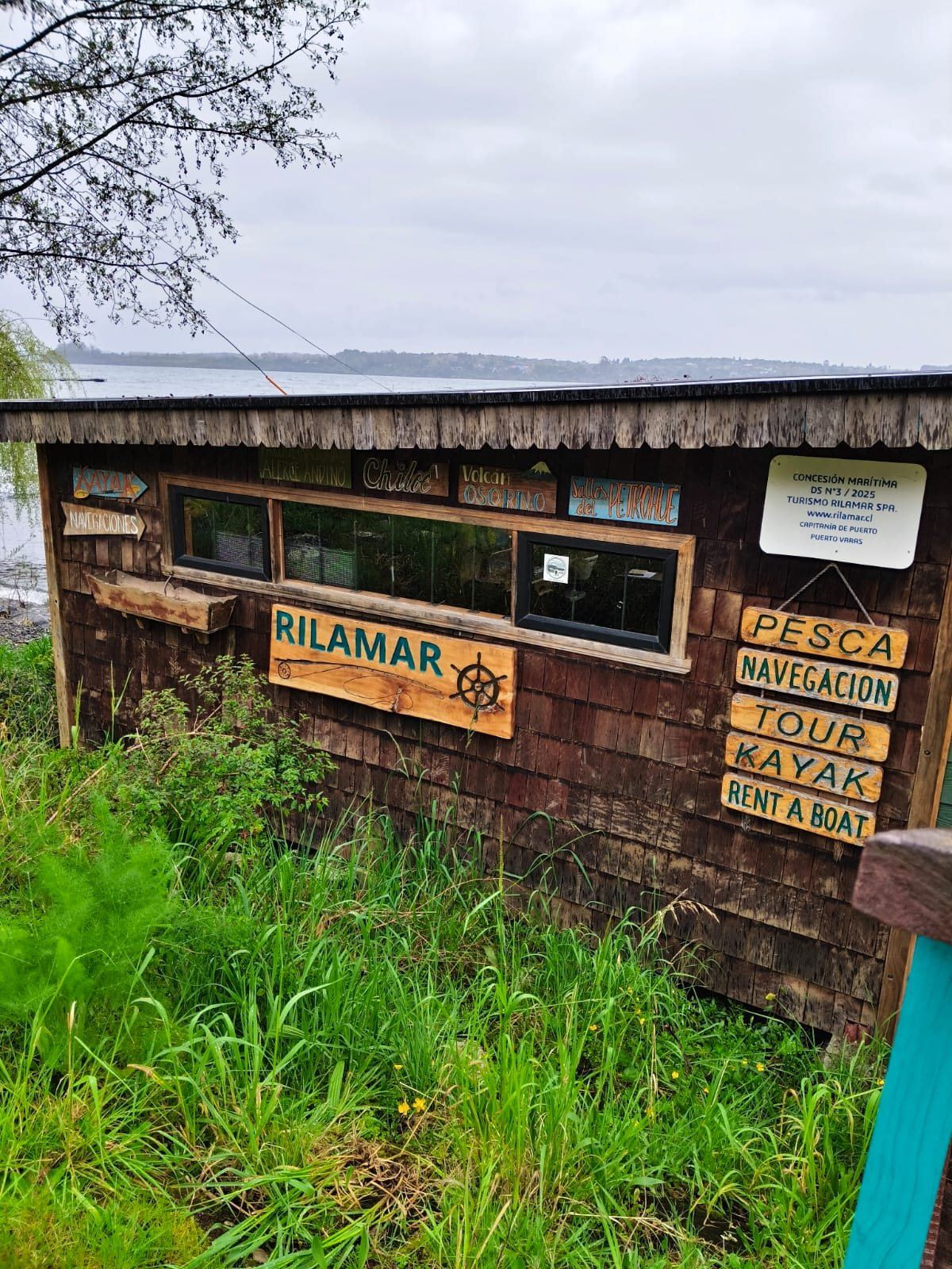 Fachada do escritório Rilamar com placas de madeira: pesca, navegação, tour, caiaque e aluguel de barcos
