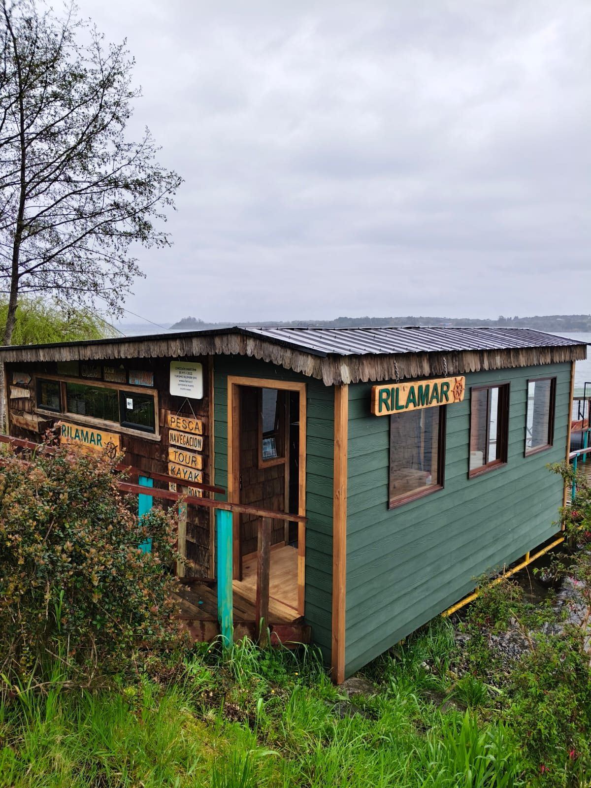 Escritório Rilamar renovado, de madeira verde com placa entalhada, às margens do Lago Llanquihue