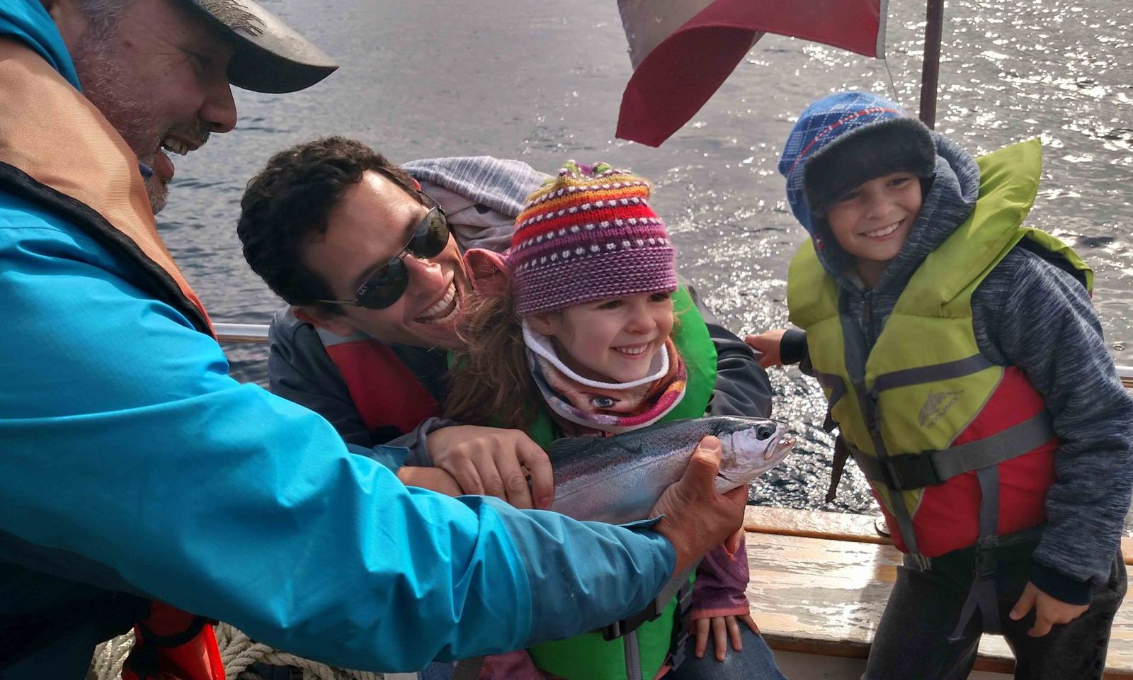 Família a bordo segurando uma truta recém-pescada, antes de devolvê-la ao lago